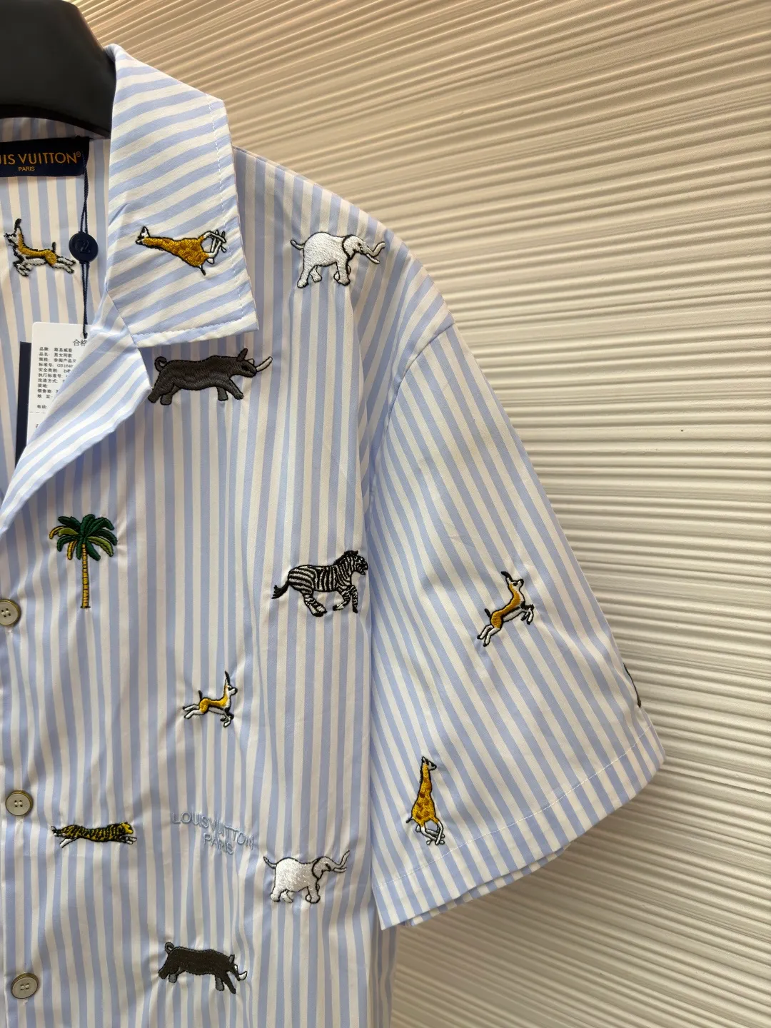 LOUIS VUITTON nostalgic style embroidered striped short-sleeved shirt with animals and plants ●Original version: Purchased and developed by 16815 ●Item number: 1682514-A65 ●Fabric: cotton fabric ●Technology: embroidery production ●Color: blue ●Version: fitted version ●Weight: about 220 grams ●Size: S-M-L-XL ●Description: This LOUIS VUITTON striped animal embroidery short-sleeved shirt is made of high-count pure cotton poplin fabric. After pre-washing process, it feels smooth and breathable. It has both drape and stiffness, and is not easy to wrinkle and deform. The blue and white vertical stripes on the body are woven with yarn-dyed technology, and the texture is clear and does not fade. The animal and coconut tree patterns are presented with sophisticated embroidery technology. The embroidery threads are full of color and the stitches are dense. The patterns are three-dimensional and vivid, forming a rich visual hierarchy with the stripe base. The shirt has a Cuban collar style, with smooth necklines, custom mother-of-pearl buttons at the placket, and a warm texture. The overall shape is loose, the shoulder joints are straight and fine, the cuffs are cuffed with exquisite craftsmanship, custom accessories and three logos are complete, and the details are full of luxury craftsmanship. It is suitable for casual vacations and daily outings, etc. The overall wiring is straight and delicate, the fabric is comfortable and soft, and the color is consistent without color difference. It can be matched with the same style to create a fashionable look and control various occasions. Customized accessories, complete with three standards, same style for men and women!